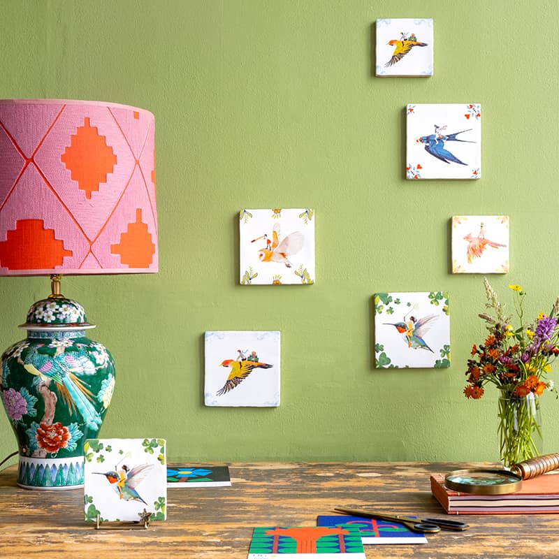 Kleurrijke tegeltjes met vogelmotieven op groene muur gepresenteerd