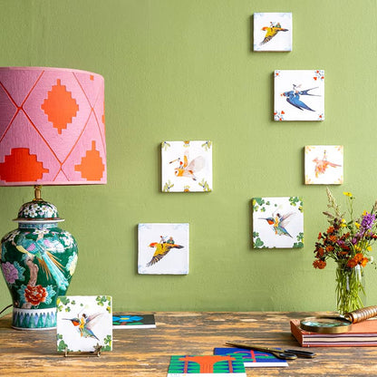 Kleurrijke tegeltjes met vogelmotieven op groene muur gepresenteerd